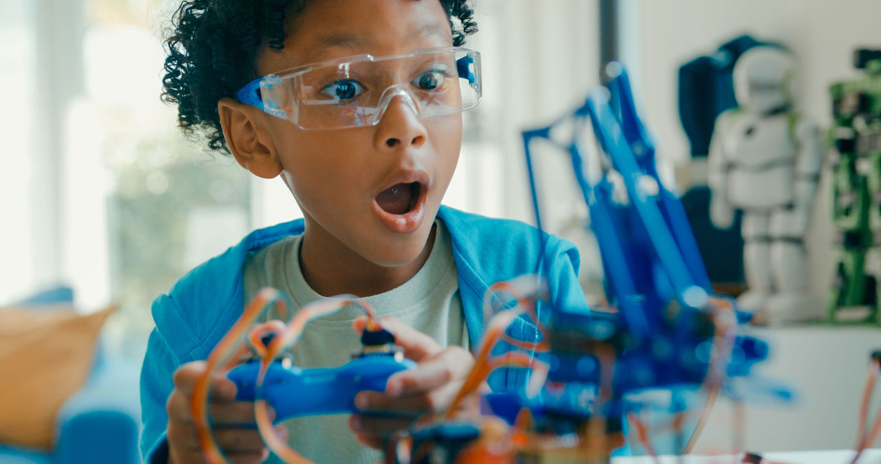 African American Inventors A young African American boy wearing safety goggles looking surprised at a science experiment