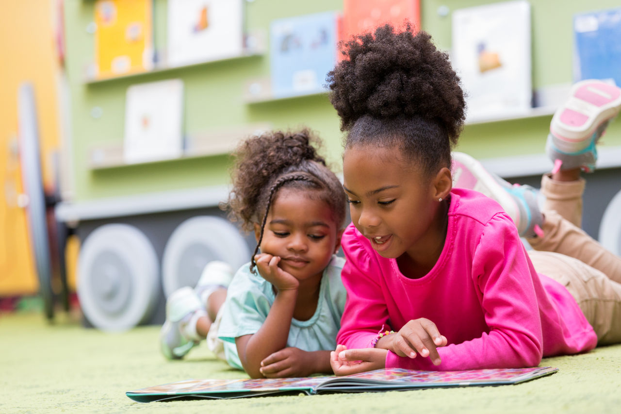 Ways to Celebrate Black History Month Two African American girls lying on the floor reading a book together